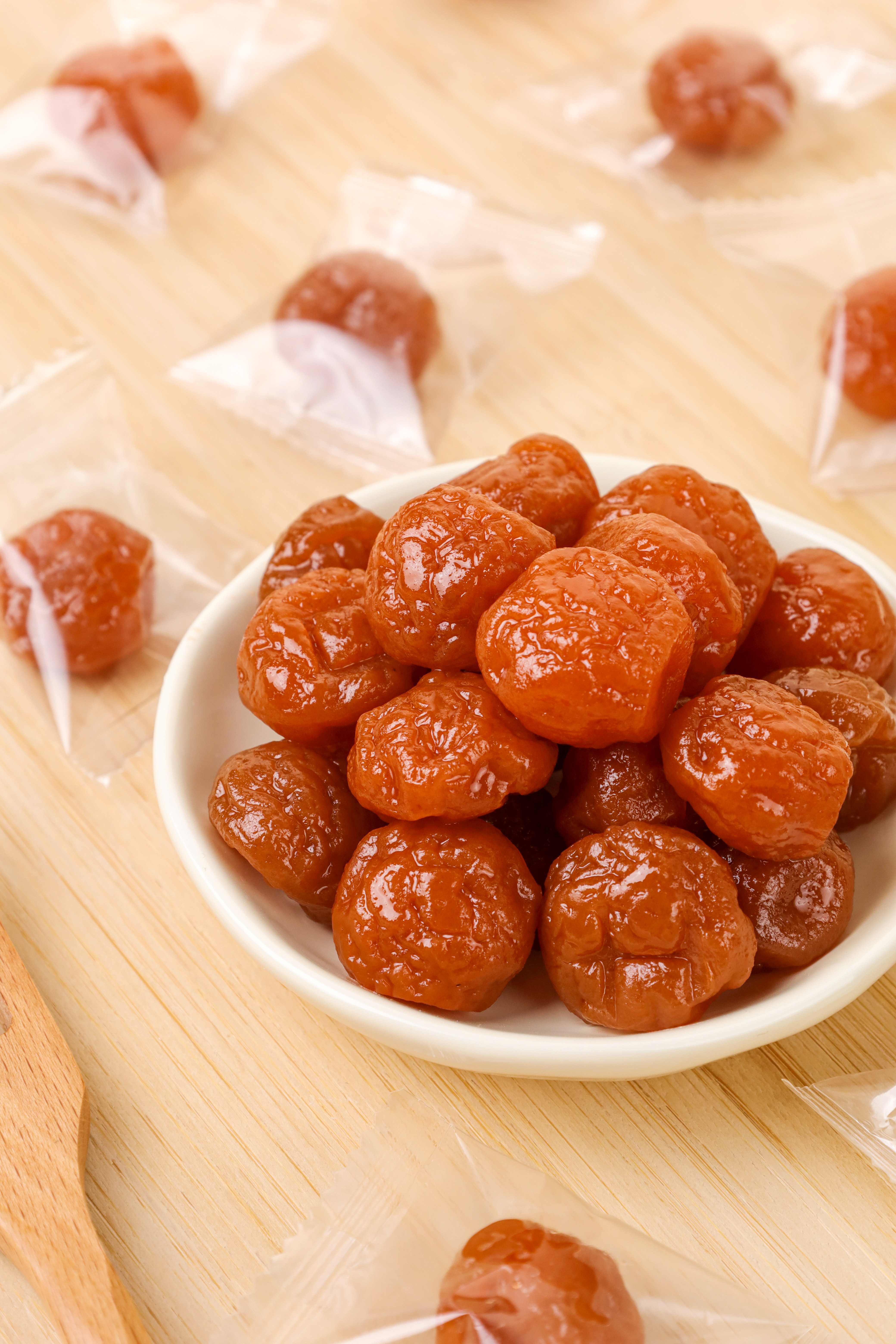 AGOLYN Dried Plum Candy Overhead Display - Individual Wrappers on Wooden Surface